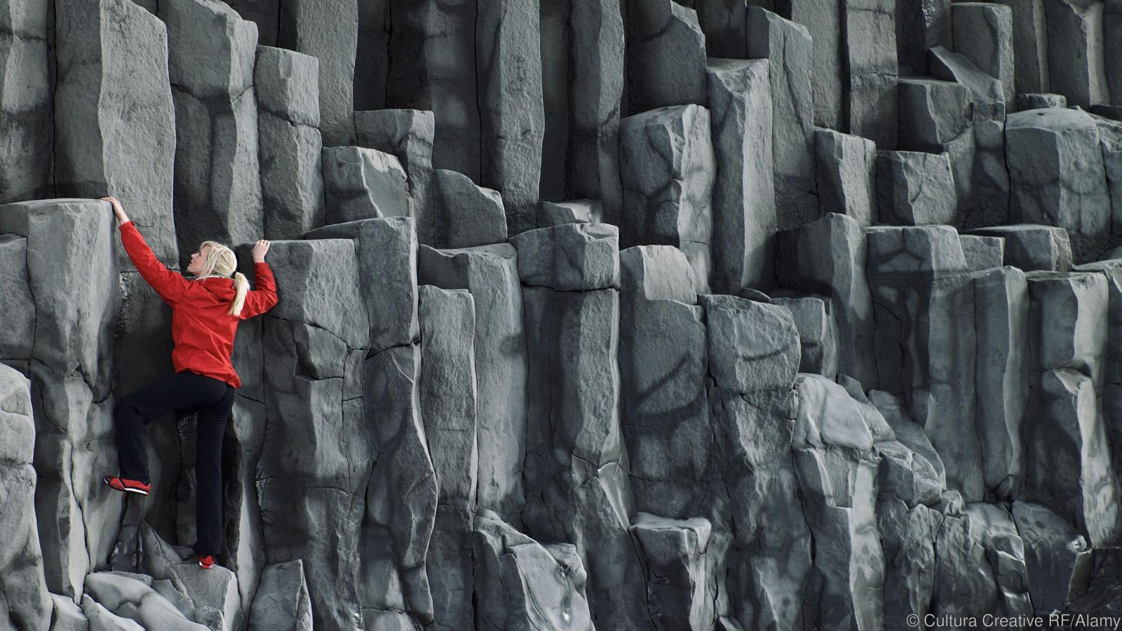 Woman climbing basalt columns